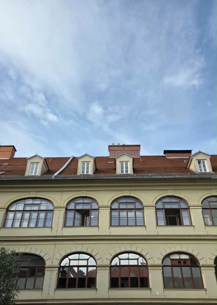 Fassade eines Altbaus mit großen historischen Holzfenstern und Rundbögen