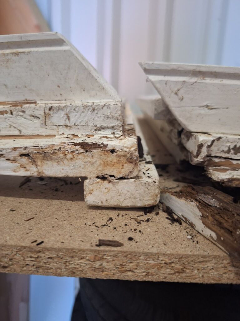 Schadstellen und abblätternde Beschichtung an alten Holzfensterteilen